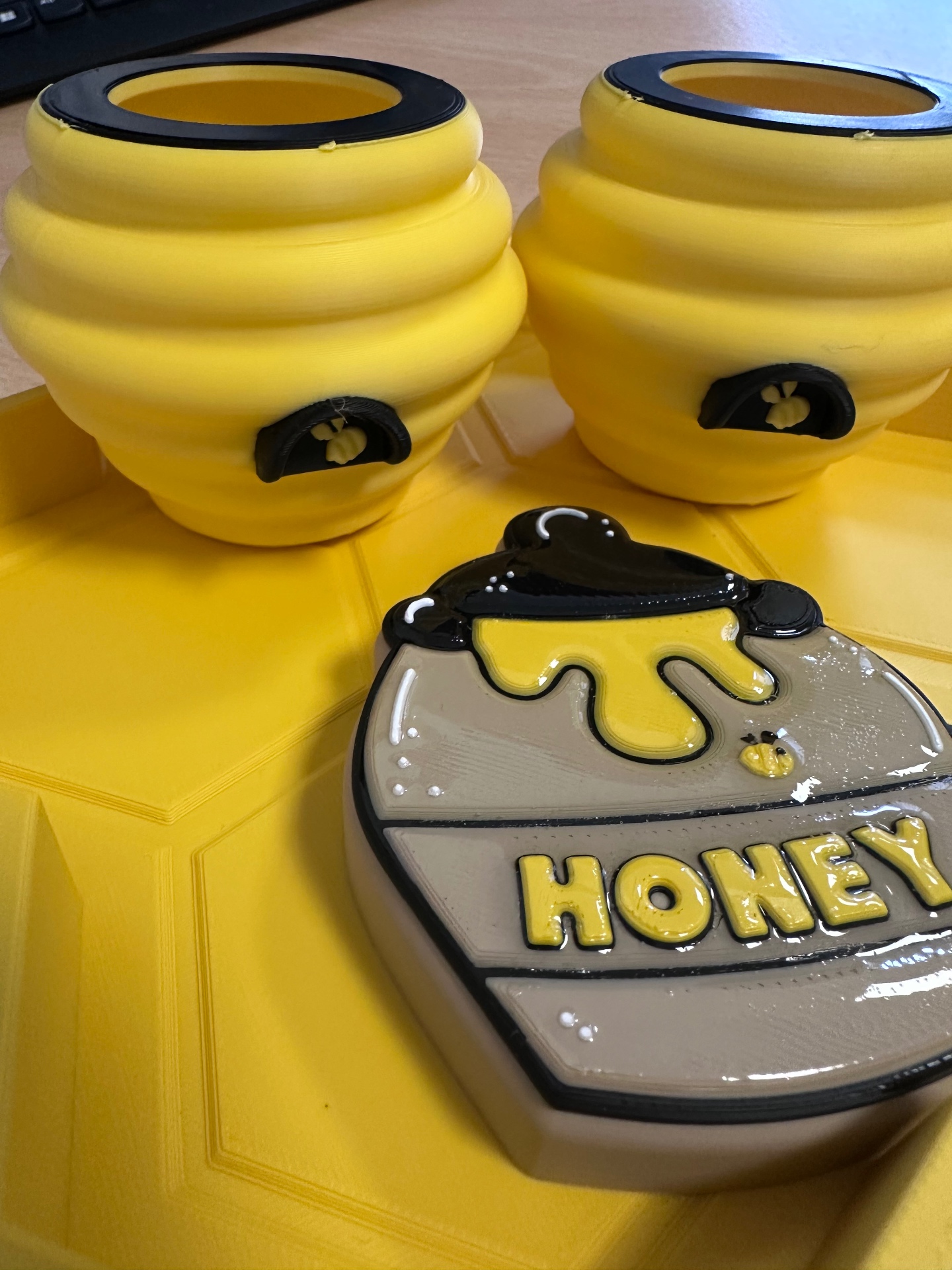 Close up of the honey pot piece resting on the yellow honeycomb tray with beehive pieces behind